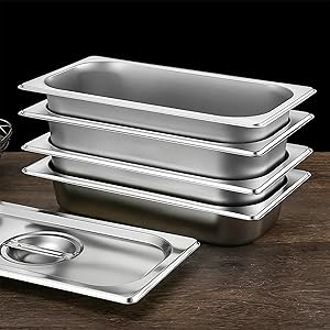 Ensemble de casseroles en acier inoxydable de différentes tailles, empilées sur une surface en bois foncé. Comprend un couvercle de casserole.