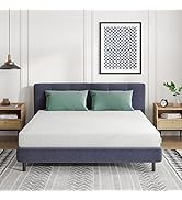 Chambre moderne avec cadre de lit rembourré bleu marine avec coussins décoratifs verts, décoration murale géométrique et éclairage suspendu.