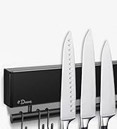 Porte-couteaux magnétique fixé au mur présentant trois couteaux de cuisine en acier inoxydable avec manches blancs.