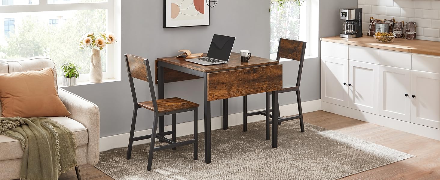 avec table en bois, deux chaises et design à abattant. Monture métallique de style industriel. Placé dans le coin cuisine avec canapé visible.