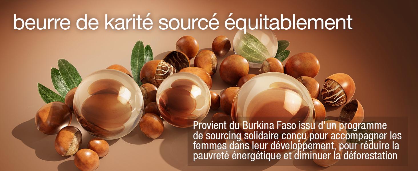 Le texte se lit comme suit : « beurre de karité sourcé équitablement ». Noix ou graines sphériques brunes disposées avec des feuilles sur une surface en bois.